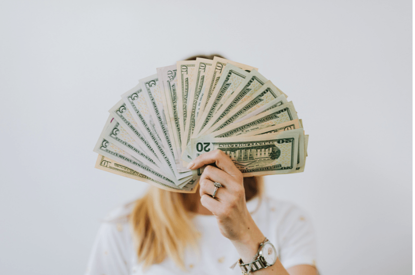 negatywne przekonania o pieniądzach - kobieta z plikiem pieniędzy